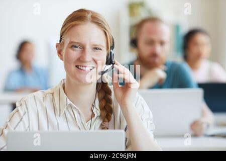Portrait of young operator in headset smiling at camera she consulting clients Stock Photo