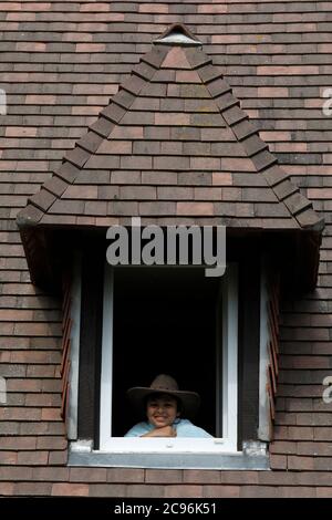 Boy looking out of a window in Eure, France. Stock Photo