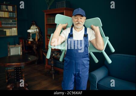 Elderly cargo man in uniform holds child chairs Stock Photo
