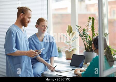 Group of medical workers discussing their work together in team while working in medical call center Stock Photo