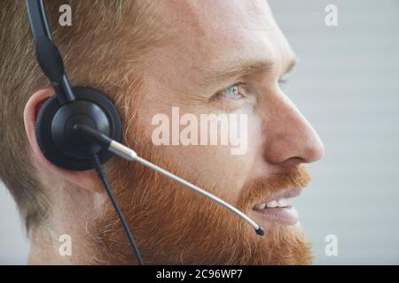 Close-up of bearded man in headphones talking on the phone he working in call center Stock Photo