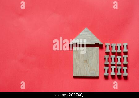 Wooden house from a children's constructor on a coral background. Simple house made of wooden geometric details. View from above. Copy space. Stock Photo