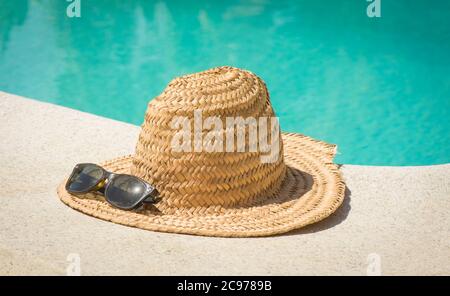 Vintage straw hat with sun glasses at the border of a swimming pool in ...