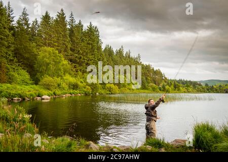 An action shot of a fly fisherman casting a pike fly on Loch Stroan, Galloway Scotland