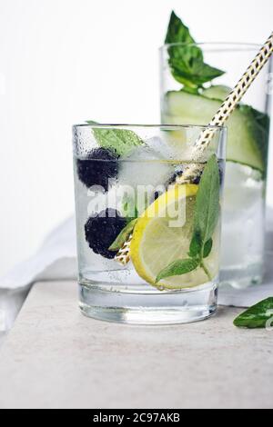 Summer refreshing drink, tonic with lemon, blackberry, cucumber and basil leaves on a light background. Stock Photo