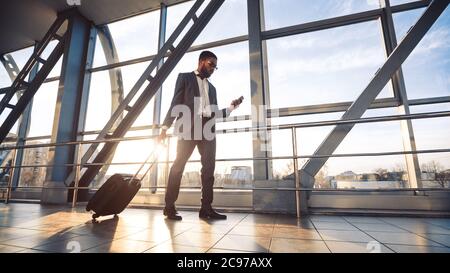 Man Using Phone And Business App Walking To Airport Gate Stock Photo