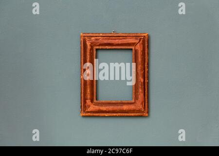 Small moulded rectangular vintage wooden frame hanging in the center on a teal colored wall Stock Photo