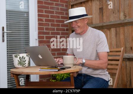 Happy man using laptop in garden Stock Photo