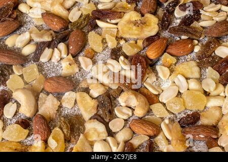 Mix of nuts and dried fruits on a stone gray background. Peanuts, candied pineapples, raisins, dried bananas, figs, almonds. Stock Photo