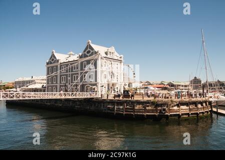 Cape Town, South Africa, February 17 2017: People walking over the bridge by African Trading Port building in the Waterfront on a sunny summer day. V& Stock Photo