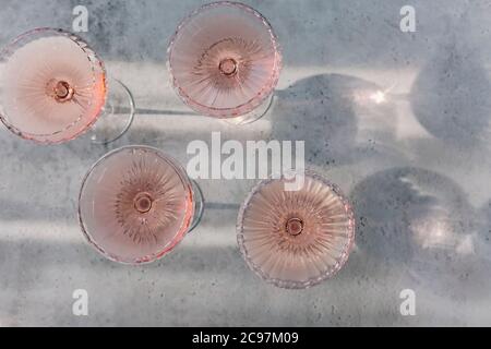 Top view of glasses with cold pink champagne placed on table near cubes of ice during party on summer day Stock Photo