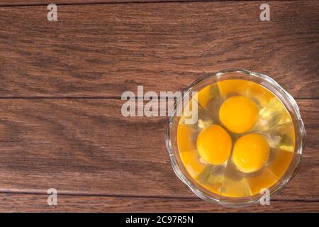 Three raw eggs in a glass bowl. The contents of chicken eggs for cooking eggs and other dishes. Stock Photo