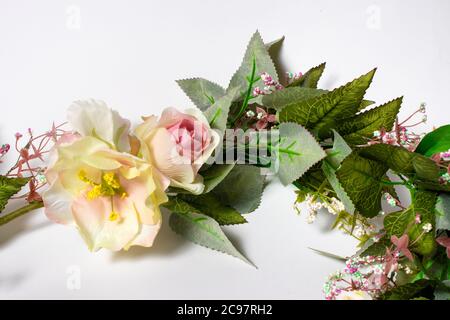 Artificial flowers on a white background. Pink and yellow roses. Stock Photo