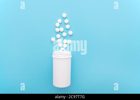 Medical background with white bottle and pills on blue surface, top view, space for text, concept picture Stock Photo