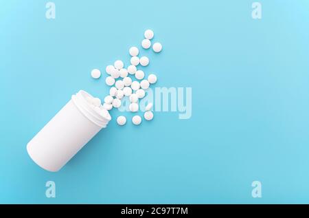 Medical background with white bottle and pills on blue surface, top view, space for text, concept picture Stock Photo