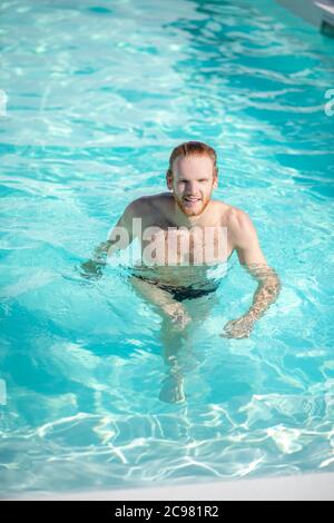 Young happy man walking in water in pool Stock Photo