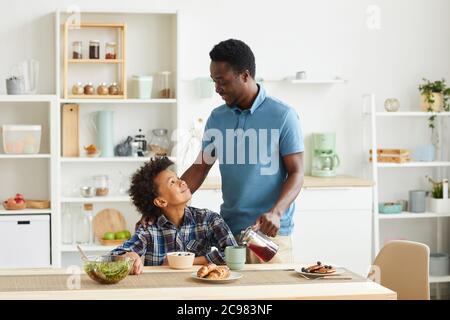 African family of two father and son having breakfast together in domestic kitchen Stock Photo