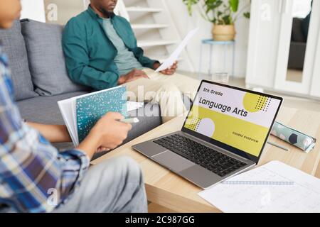 Close-up of child sitting on sofa and using laptop computer for his online education with father sitting in the background in the living room Stock Photo