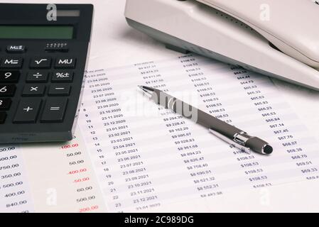 Calculator, pen and phone on financial papers with numbers and money. Company report, marketing research, expenses and income of the company. Business Stock Photo