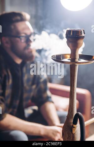 close up photo of a narghile. blurred bearded guy on the background of the photo. tool. device for smoke. Stock Photo
