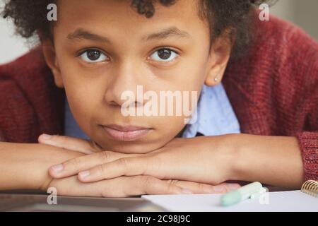 Close-up of African boy looking at camera while lying on the desk he tired of study Stock Photo