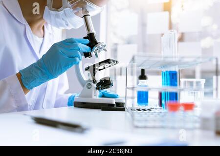 Young Asian scientist Working looking through a  microscope doing research for analyzing a Experiments sample in a forensic laboratory Stock Photo