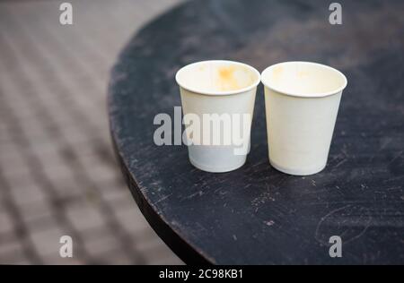 Two plastic glasses with coffee stand on the street on a wooden table. Close-up Stock Photo
