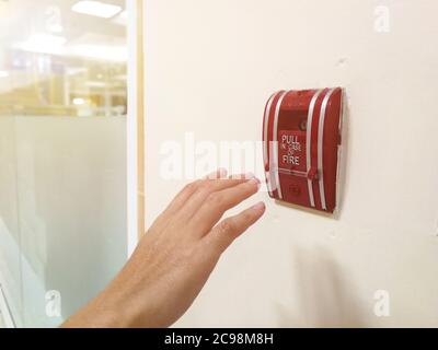 The hand of man is pulling fire alarm on the wall Stock Photo