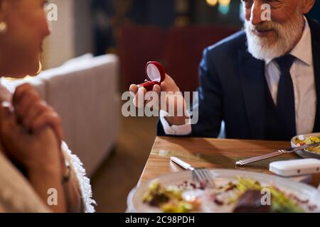 Will you marry me. Senior marriage proposal Senior man happily looks woman waiting answer marriage proposing. Elegant male in suit smile holding ring, Stock Photo