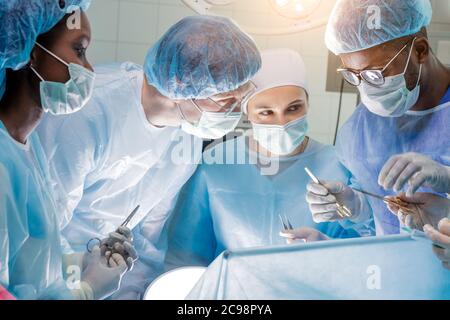 hardworking team of surgeons at work in operating room.profession, job, occupation concept Stock Photo