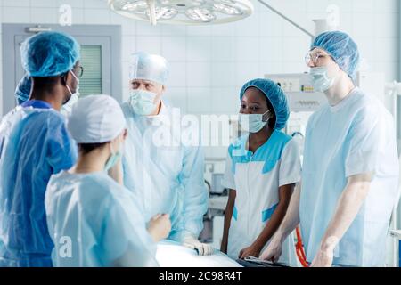 skilled experienced doctor teaching multiracial interns. close up photo.leader of doctors giving directions to his colleagues Stock Photo
