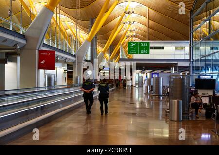 28th July 2020, Barajas Airport, Madrid, Spain: Civil Guards / Guardia Civil officers walk through the near empy departure gates lounge area of the Terminal 4S building of Barajas Airport. Reduced numbers of flights are now operating between European countries after the lockdown to control the covid-19 coronavirus, and governments have put a system of air bridges in place to facilitate travel and tourism. Spain has seen a number of new outbreaks in recent days, prompting the UK government to announce that people returning to the UK from Spain should quarantine for 14 days on arrival.. Stock Photo