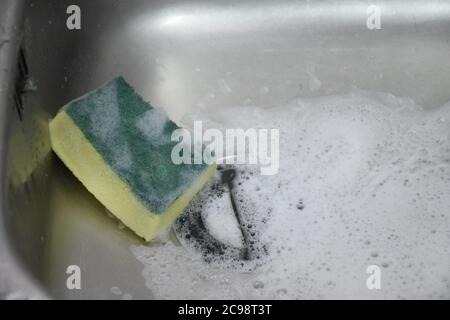 Scouring pad or Scourer with foam in sink. Stock Photo
