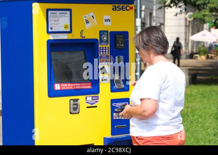 Warsaw Poland a woman buy public transport tram tickets from a street corner ticket machine in July 2020 Stock Photo