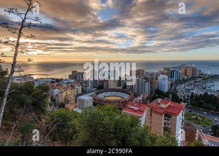 Spanish coast in Andalusia in the morning. View over the city of Malaga at sunrise with clouds and an orange horizon. City view on the Costa del Sol f Stock Photo