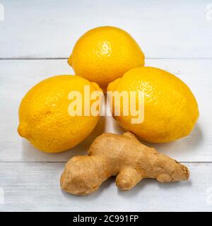 three lemons and ginger root on white wooden background Stock Photo