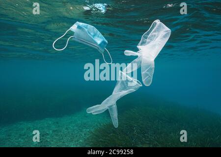 Disposable gloves and face mask underwater, plastic waste pollution in the sea since coronavirus COVID-19 pandemic Stock Photo