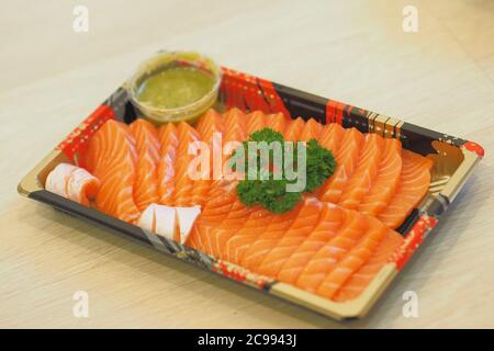 Soft Focus to Sashimi salmon topping with Parsley and Thai Seafood Dipping Sauce on Japanese Plastic Plates Stock Photo