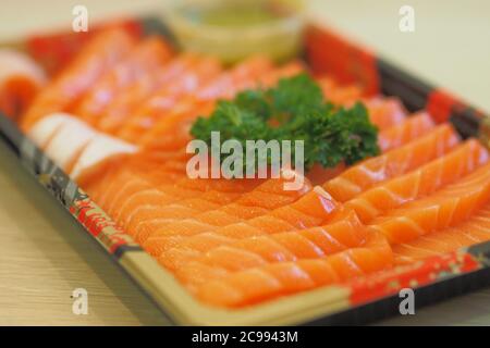 Soft Focus to Sashimi salmon topping with Parsley and Thai Seafood Dipping Sauce on Japanese Plastic Plates Stock Photo