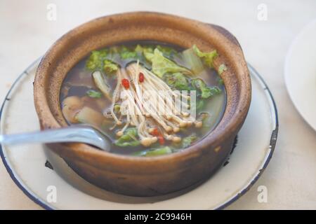 Bak kut teh or Hokkiens topping with golden needle mushroom or Enokitake in Earthenware pot in broth popularly served in Malaysia ,Singapore Stock Photo