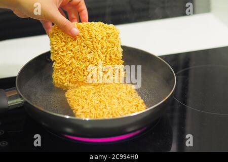 Salary man is boiling instant noodles for dinner. Stock Photo