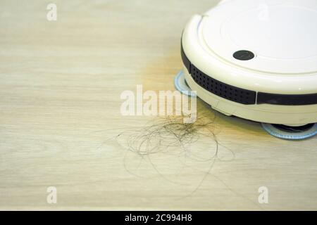 The robot vacuum cleaner is cleaning floor. Stock Photo