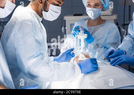 Pre oxygenation for general anesthesia. Surgery equipment, doctors in uniform and scrub cap on head being ready for operating Stock Photo