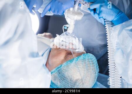 anesthesiologist gives the mask inhalation anesthesia to a male caucasian patient Stock Photo