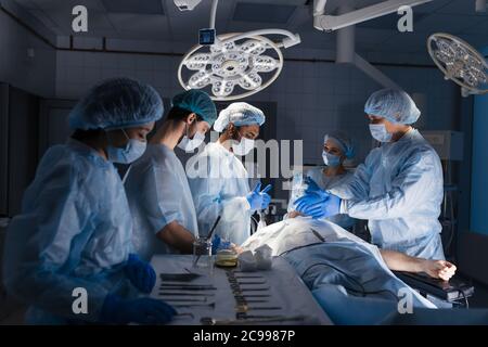 The anesthesiologist team takes care of patient lying on operation table. The nurses and surgeon, all the assistants are waiting around. Stock Photo