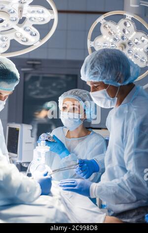 Group of concentrated surgeons engaging in rescue of male patient in operation room at hospital, emergency case, surgery, medical technology, health c Stock Photo