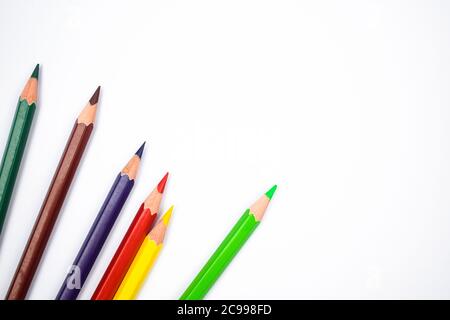 Five various colored wood pencil crayons placed on a white isolated paper background Stock Photo