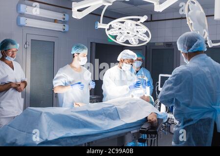 Medical Team Performing Surgical Operation in Bright Modern Operating Room. pre oxygenation for general anesthesia. Caucasian patient receives anaesth Stock Photo