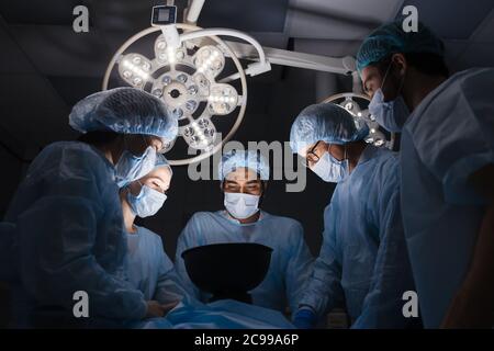 Low angle view of team of professional surgeons working at the hospital performing surgical procedure in operating theatre. Hospital, medicine, people Stock Photo