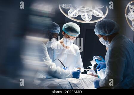 Blurred figures of surgeons in medical uniforms performing surgery in operation theatre, copyspace Stock Photo